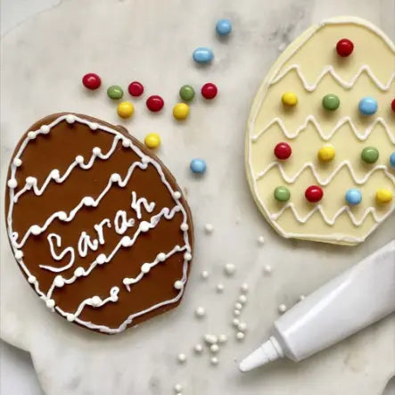 Two flat chocolate eggs decorated with icing and colourful sweets